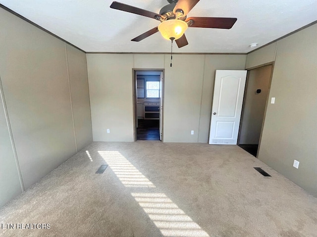 unfurnished bedroom with visible vents, crown molding, ceiling fan, and carpet floors