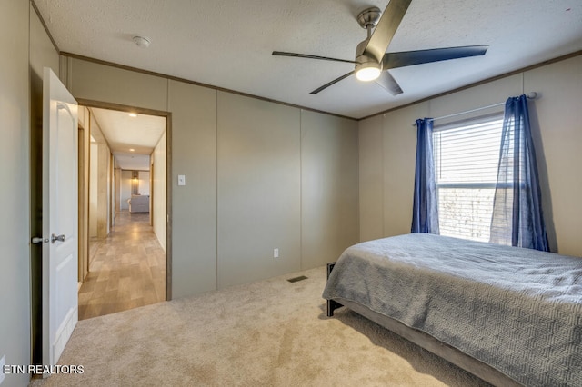 carpeted bedroom featuring a textured ceiling, ceiling fan, visible vents, and ornamental molding