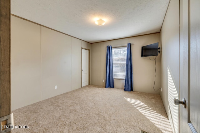 unfurnished bedroom featuring carpet flooring, a textured ceiling, and ornamental molding