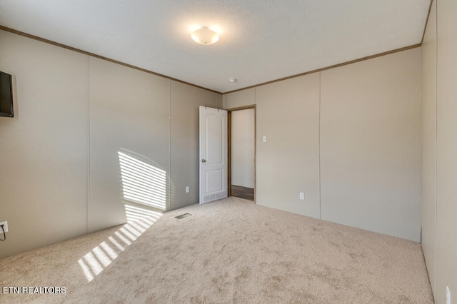 carpeted empty room featuring visible vents and crown molding