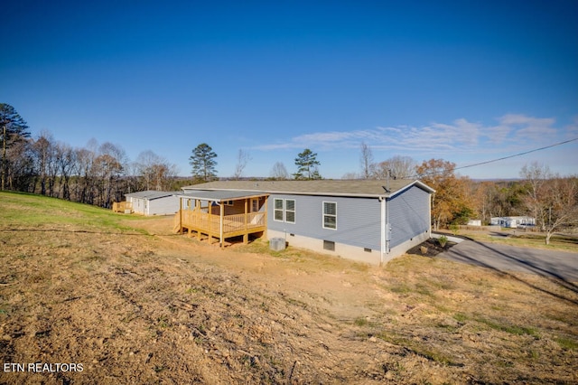 back of house featuring a wooden deck, a lawn, driveway, and crawl space