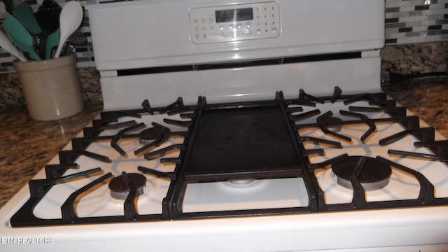 interior details with white range with gas cooktop and decorative backsplash