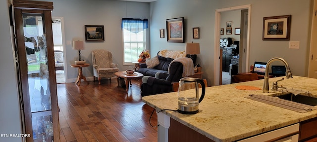 interior space featuring an island with sink, sink, beverage cooler, light stone countertops, and dark hardwood / wood-style flooring