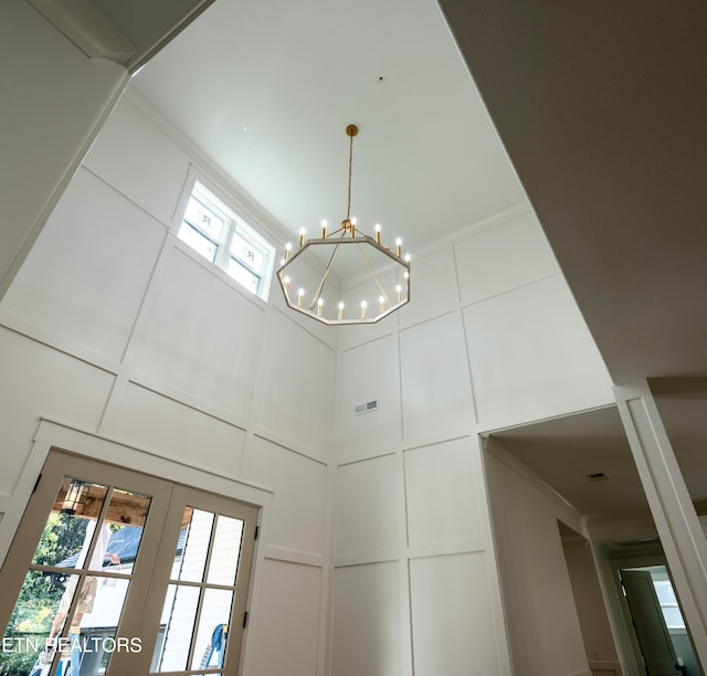 interior details featuring visible vents, a chandelier, french doors, and a decorative wall