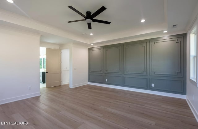 interior space with visible vents, a raised ceiling, baseboards, and wood finished floors