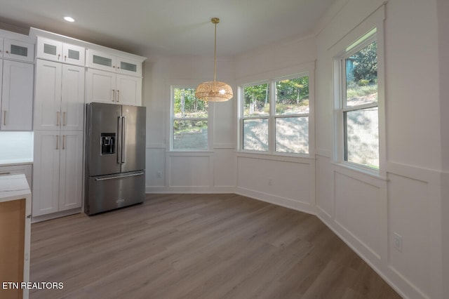 unfurnished dining area featuring recessed lighting, a wainscoted wall, light wood-style flooring, and a decorative wall