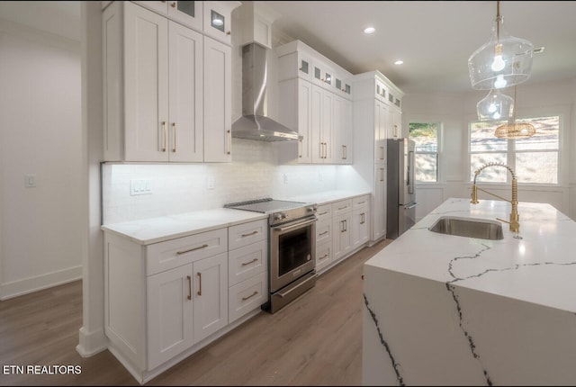 kitchen with a sink, tasteful backsplash, appliances with stainless steel finishes, and wall chimney exhaust hood