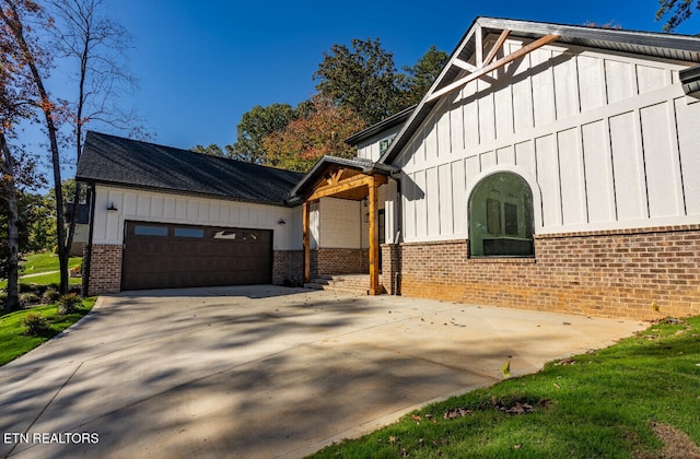 view of side of property featuring brick siding, board and batten siding, concrete driveway, and a garage