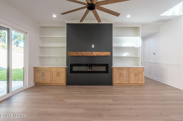 unfurnished living room featuring light wood finished floors, visible vents, built in shelves, crown molding, and a fireplace