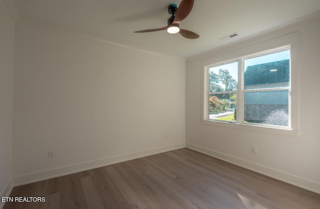 spare room with visible vents, ornamental molding, baseboards, and wood finished floors