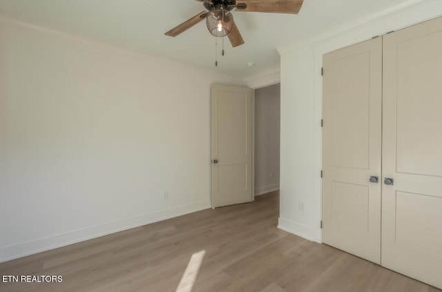 unfurnished bedroom featuring light wood finished floors, baseboards, a closet, and ornamental molding