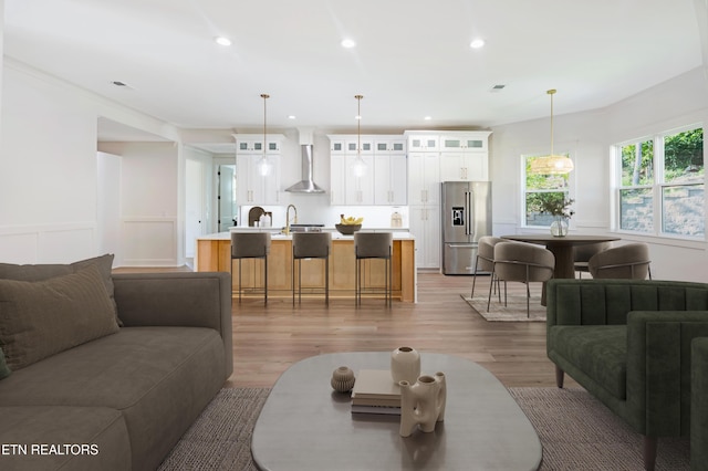 living area with recessed lighting, light wood-type flooring, visible vents, and a wainscoted wall