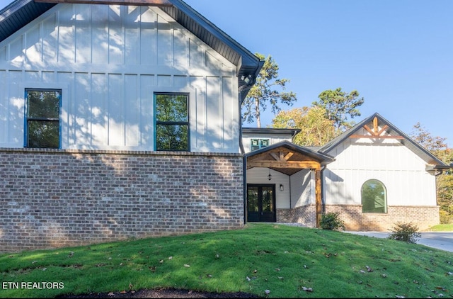 view of front of house with french doors, brick siding, board and batten siding, and a front lawn