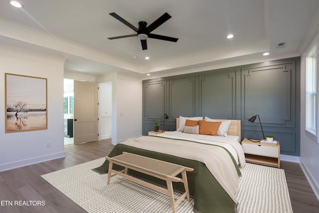 bedroom with a raised ceiling, recessed lighting, wood finished floors, and baseboards