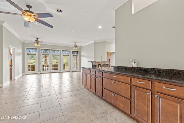 kitchen with crown molding, dark stone countertops, ceiling fan, and light tile patterned floors