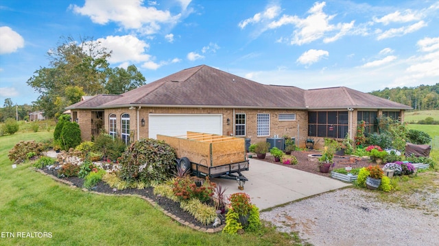 view of front facade with cooling unit, a garage, a sunroom, and a front lawn