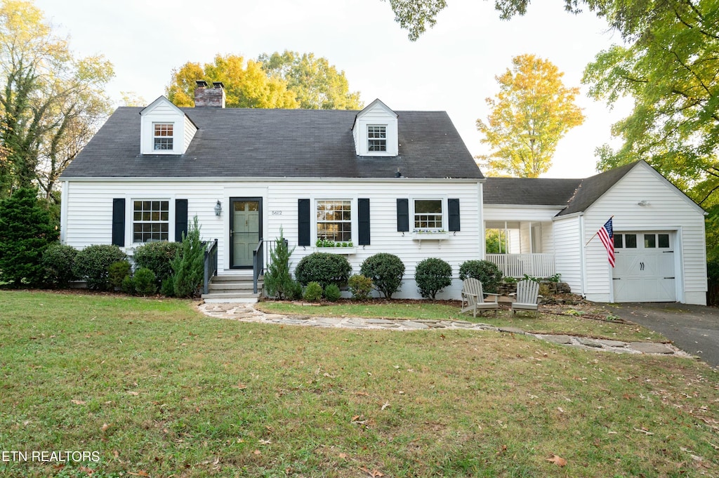 cape cod home with a front yard and a garage