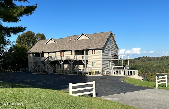 view of front of home with a front yard, a balcony, and central AC