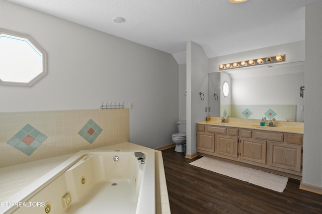 bathroom featuring vanity, a bathtub, toilet, wood-type flooring, and vaulted ceiling