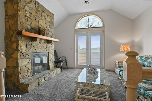 carpeted living room featuring a stone fireplace and vaulted ceiling