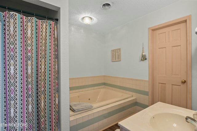 bathroom with a textured ceiling, vanity, and separate shower and tub