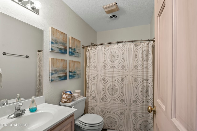 bathroom featuring a textured ceiling, curtained shower, vanity, and toilet