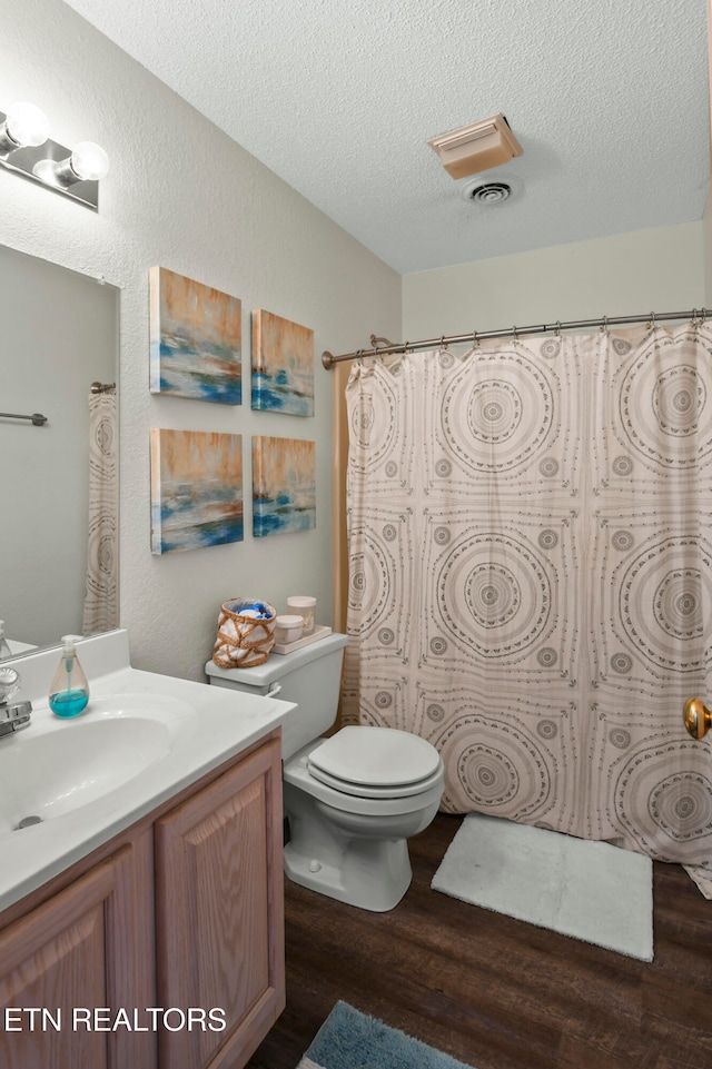 bathroom featuring vanity, wood-type flooring, a textured ceiling, a shower with curtain, and toilet