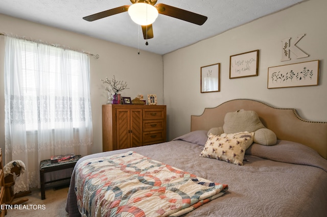 bedroom featuring carpet, ceiling fan, and a textured ceiling