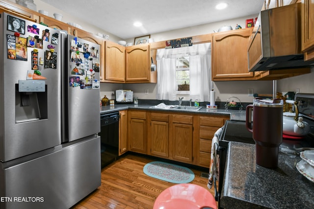 kitchen with light wood-type flooring, stainless steel fridge, black dishwasher, and sink