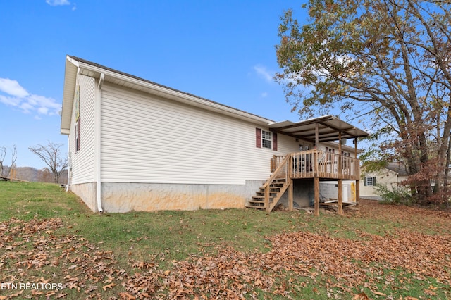 rear view of house featuring a wooden deck and a yard