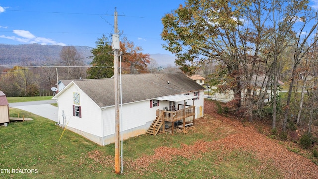 back of house featuring a lawn and a deck with mountain view