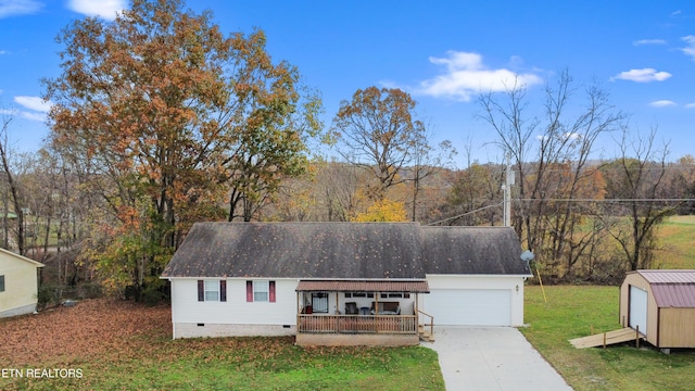 view of front of property featuring covered porch, a garage, a storage unit, and a front yard