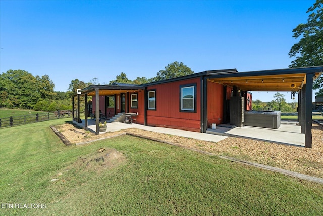 back of house with a patio area, a yard, and a hot tub