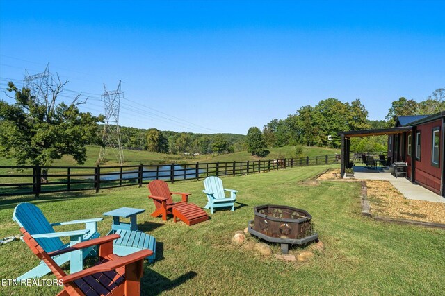 view of yard with an outdoor fire pit, a patio, and a rural view