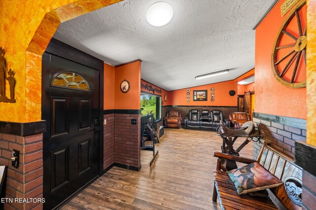 entrance foyer with vaulted ceiling, wood-type flooring, and a textured ceiling