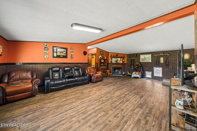 living room featuring vaulted ceiling with beams, a brick fireplace, brick wall, and hardwood / wood-style flooring