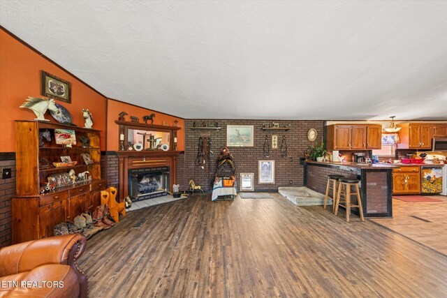 living room with brick wall, hardwood / wood-style flooring, and crown molding