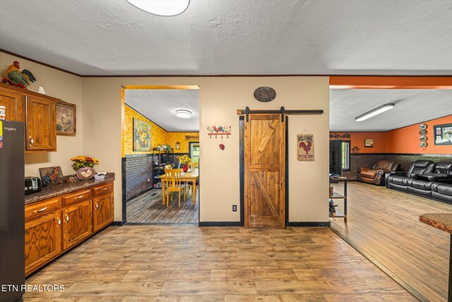 kitchen with black refrigerator, a textured ceiling, light wood-type flooring, and a barn door