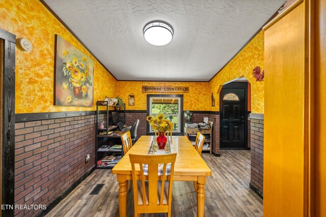 dining area with wood-type flooring and a textured ceiling