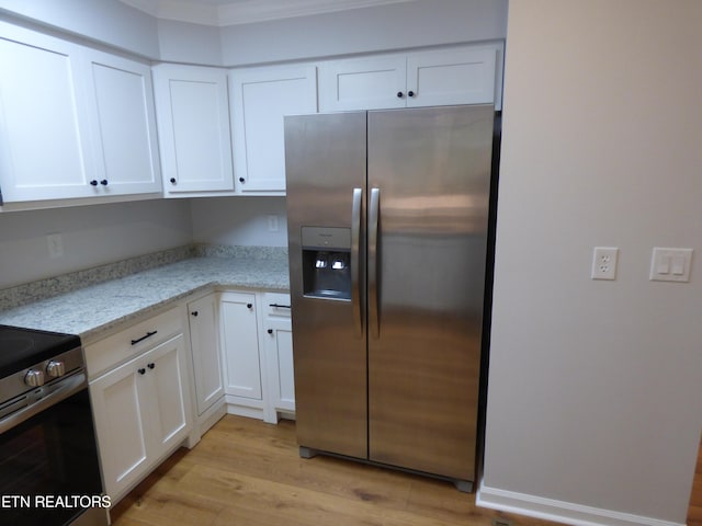 kitchen featuring appliances with stainless steel finishes, white cabinetry, light stone counters, light wood-type flooring, and ornamental molding