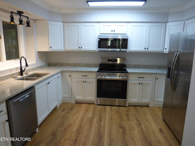 kitchen featuring stainless steel appliances, white cabinets, and crown molding