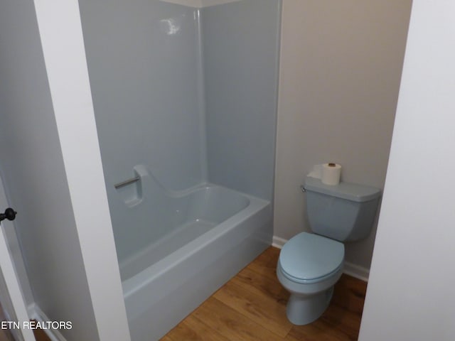 bathroom featuring washtub / shower combination, hardwood / wood-style floors, and toilet