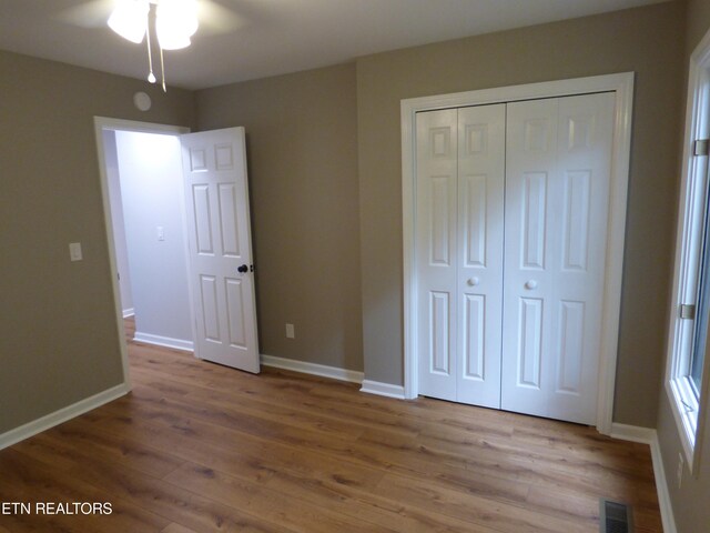 unfurnished bedroom with ceiling fan, a closet, and hardwood / wood-style floors