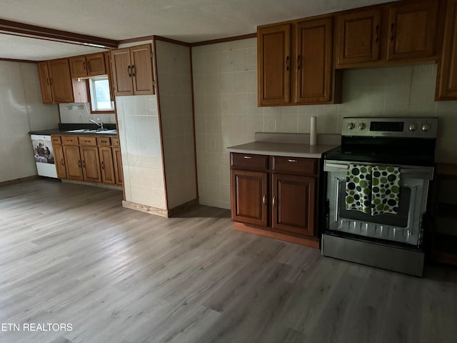 kitchen featuring washer / clothes dryer, light hardwood / wood-style floors, sink, stainless steel electric range oven, and ornamental molding