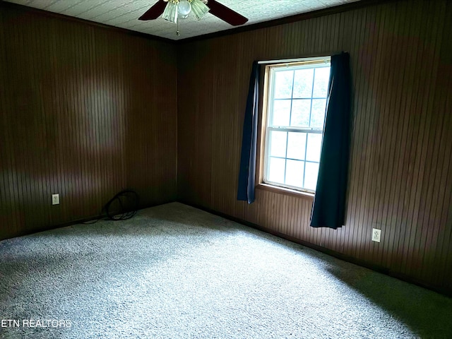 carpeted empty room featuring ceiling fan and wooden walls