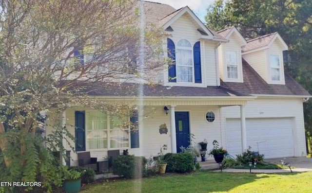 view of front of house featuring a front yard, a garage, and covered porch