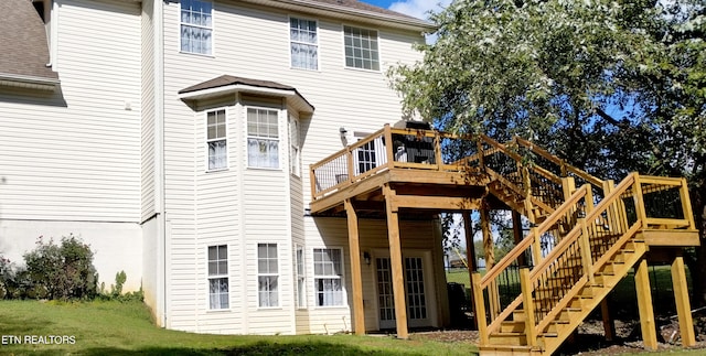 back of property with a wooden deck and a yard