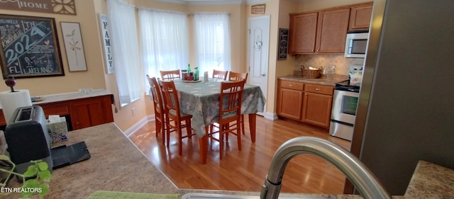 dining area with ornamental molding, light hardwood / wood-style floors, and sink