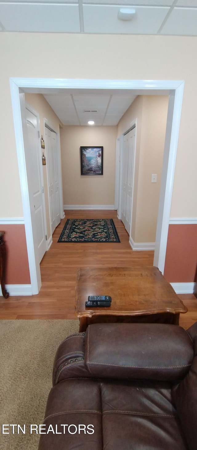 hallway with hardwood / wood-style flooring and a drop ceiling