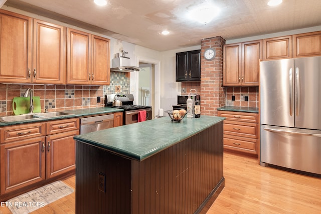 kitchen featuring appliances with stainless steel finishes, light hardwood / wood-style floors, backsplash, a center island, and sink